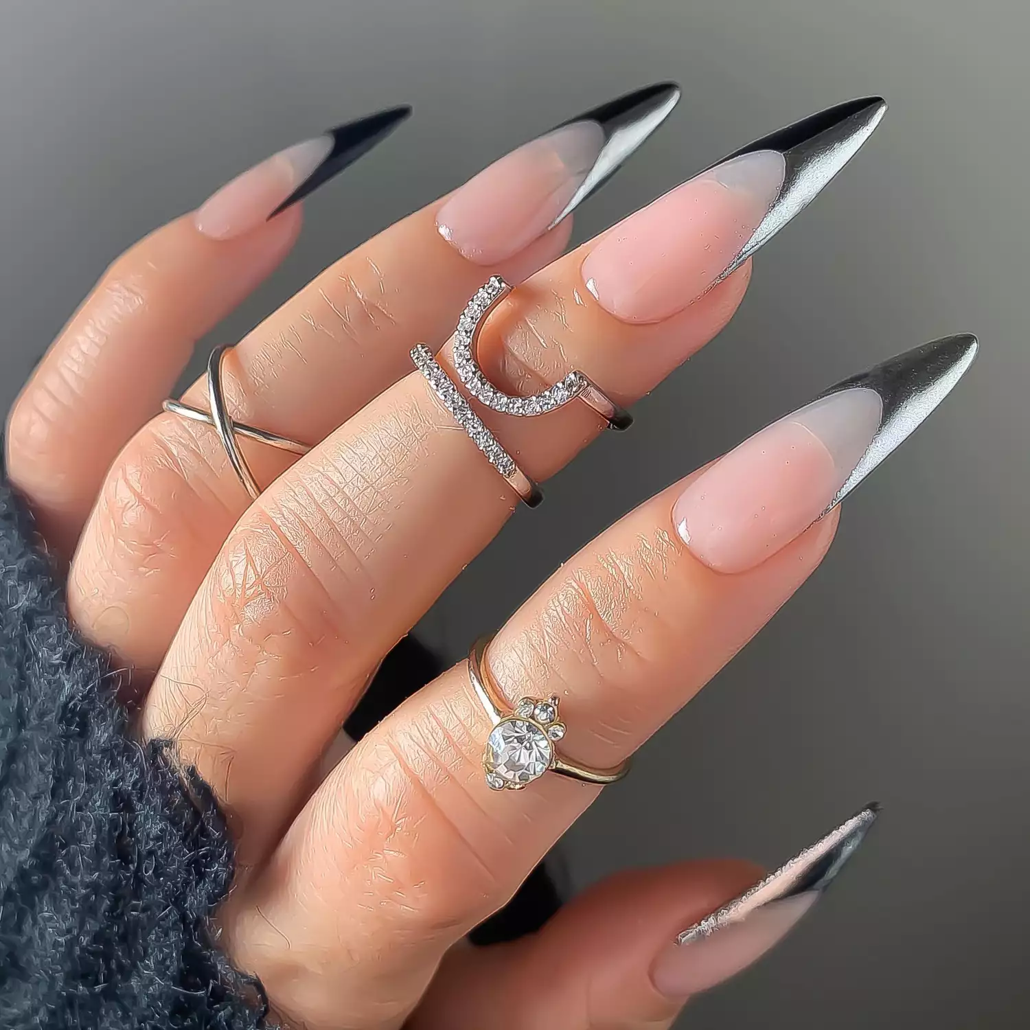 Close up of a stiletto manicure with half black, half chrome french tips