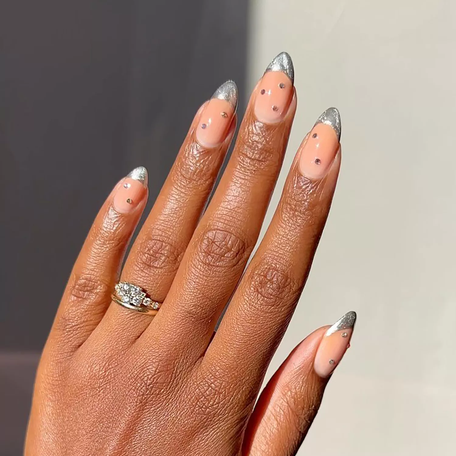 Close up of a French manicure with silver chrome tips and jewel accents