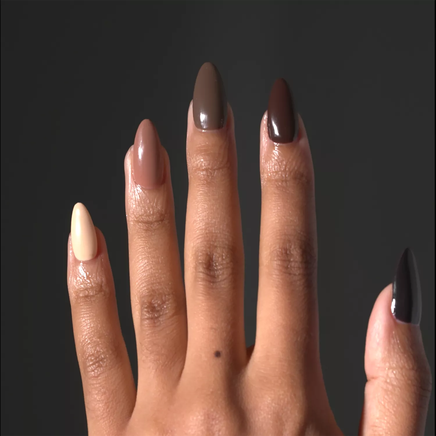 A glossy assorted chocolate manicure against a dark gray background