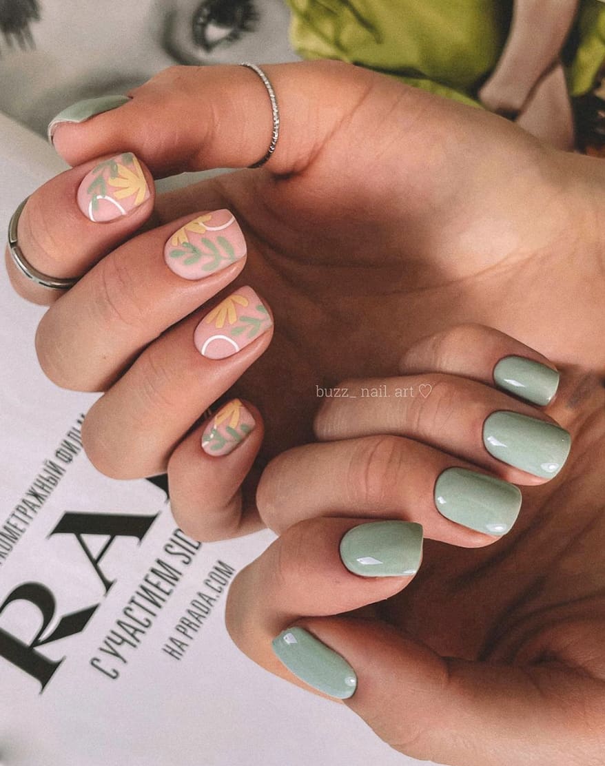 two hands with sage green nail polish and leaf accents