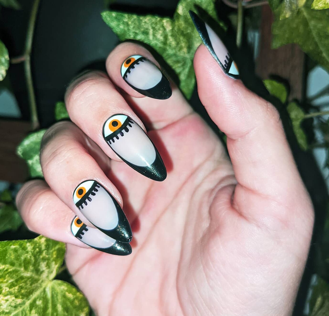 Dirty white nail polish with black French tips and evil eye nail art on long almond nails