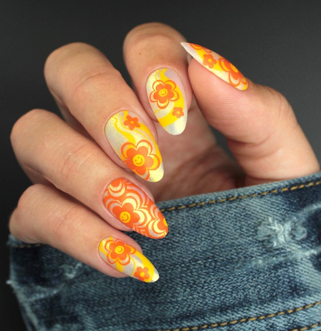 Silver chrome nail polish with yellow swirls and orange flowers on medium almond nails