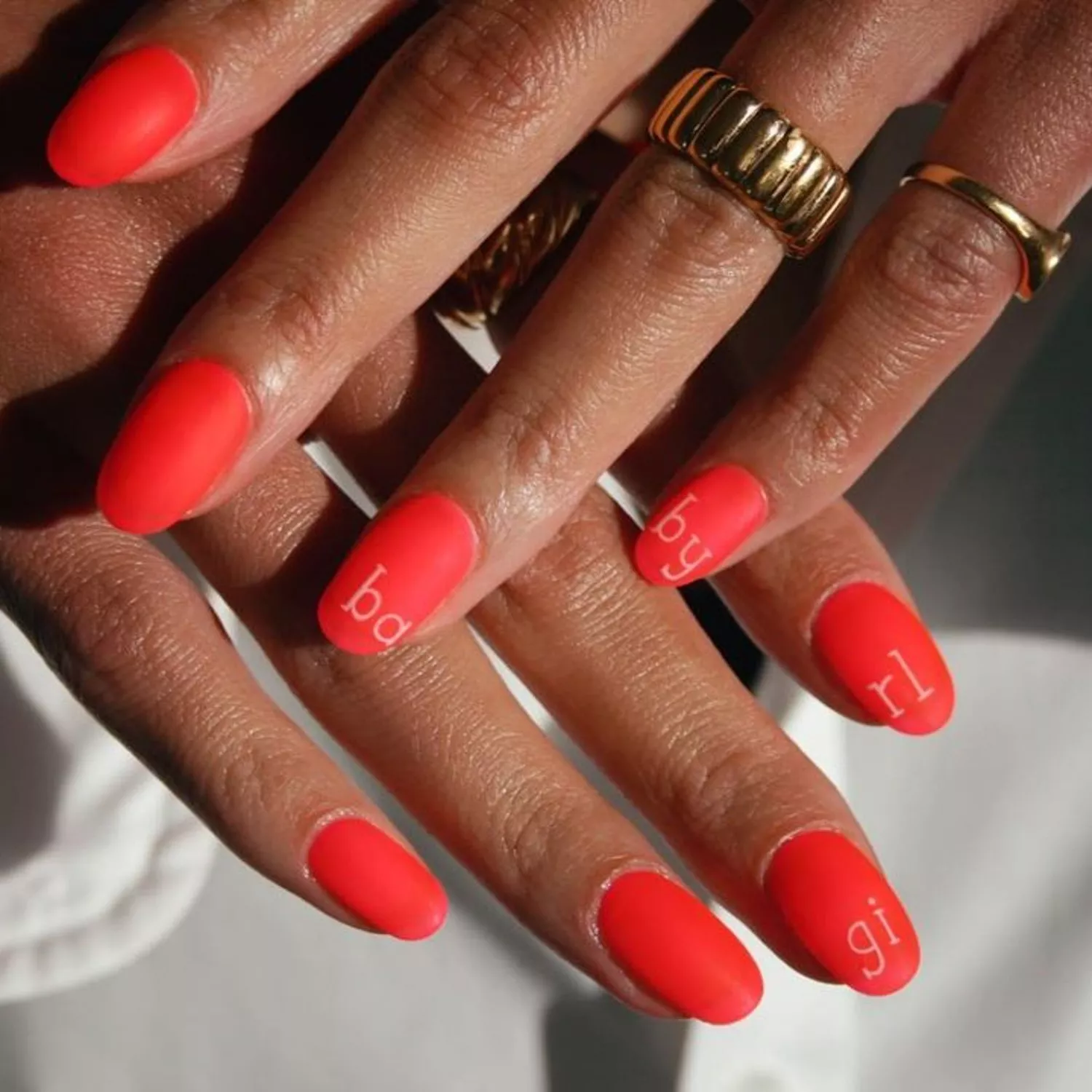 Matte red nails that say 'Baby Girl'