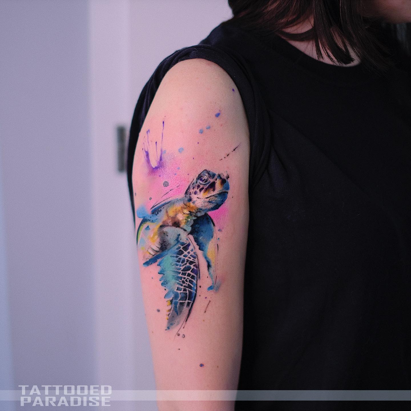 Watercolor style turtle tattoo on the upper arm