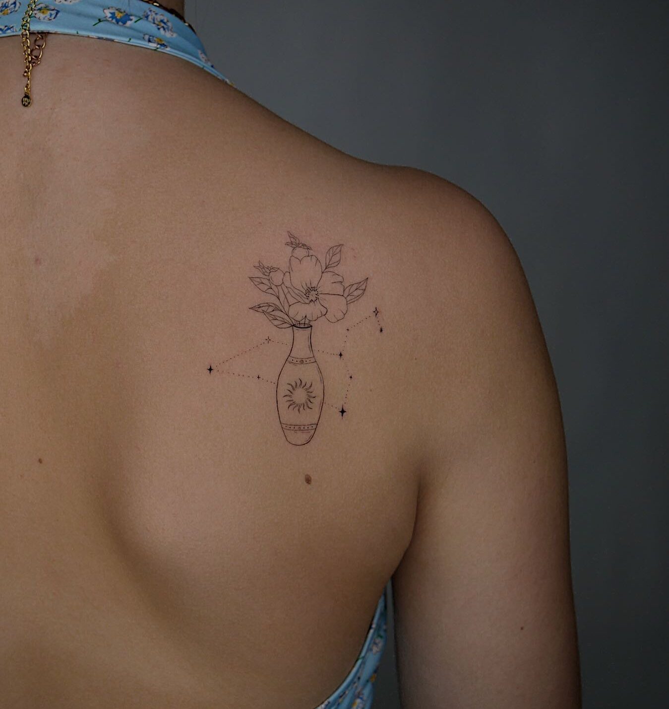 Leo constellation and flower tattoo, fine line style, located on the shoulder blade