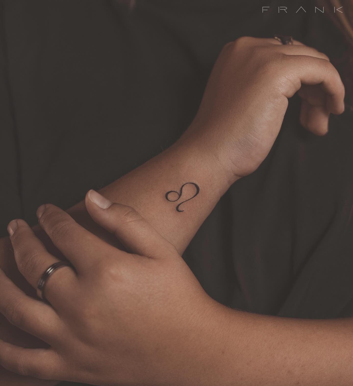 Leo zodiac symbol tattooed on the wrist, minimalistic style