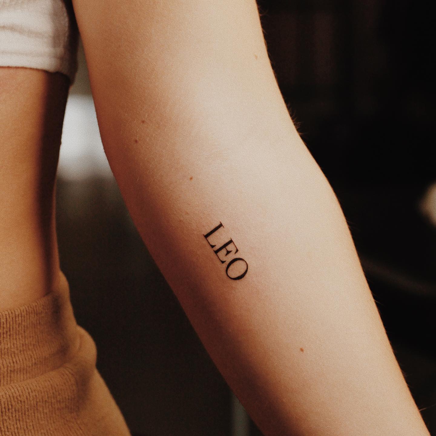 Capitalized "Leo" tattoo on the inner forearm