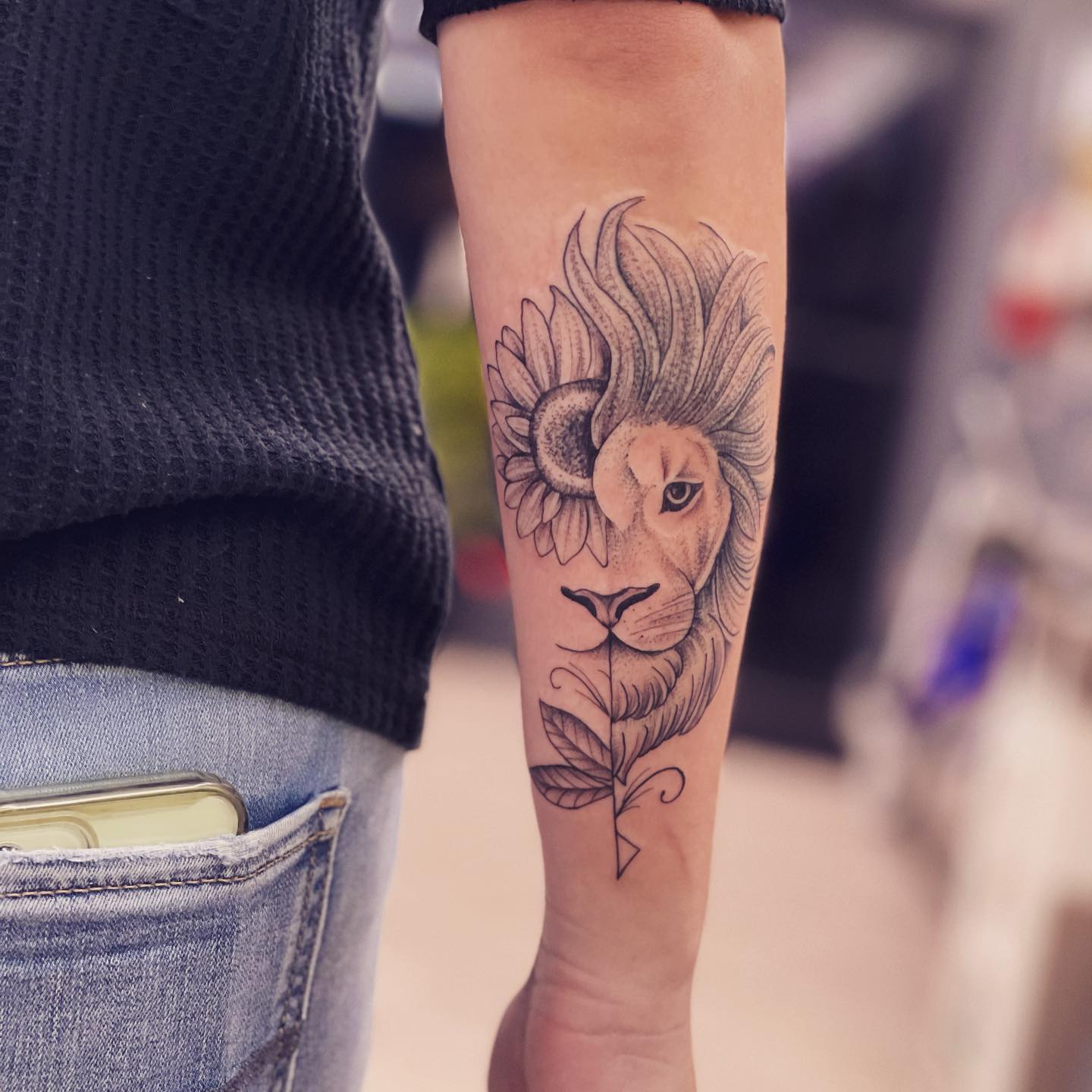 Half lion half sunflower tattoo on the outer forearm