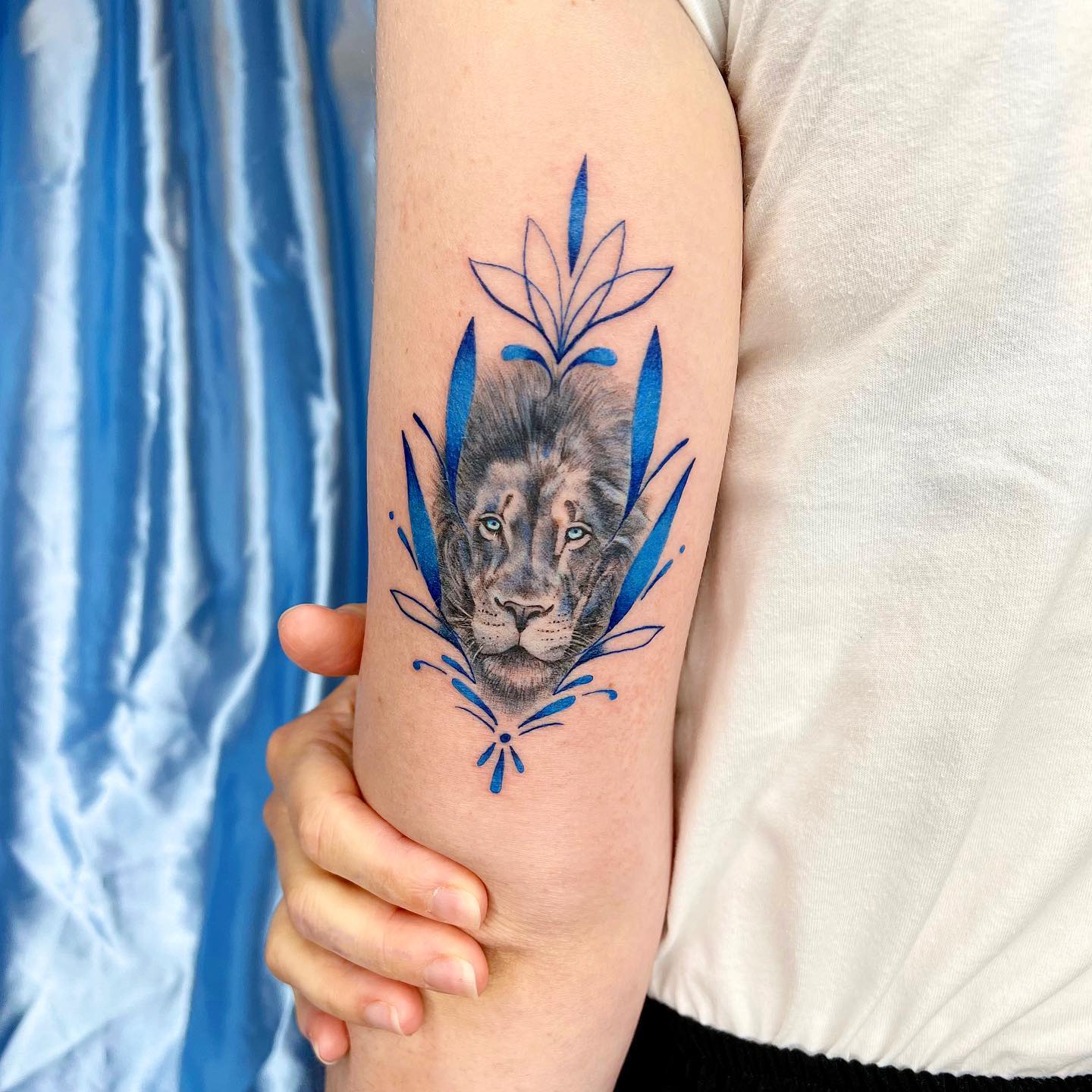 Ornamental lion portrait tattoo located on the tricep