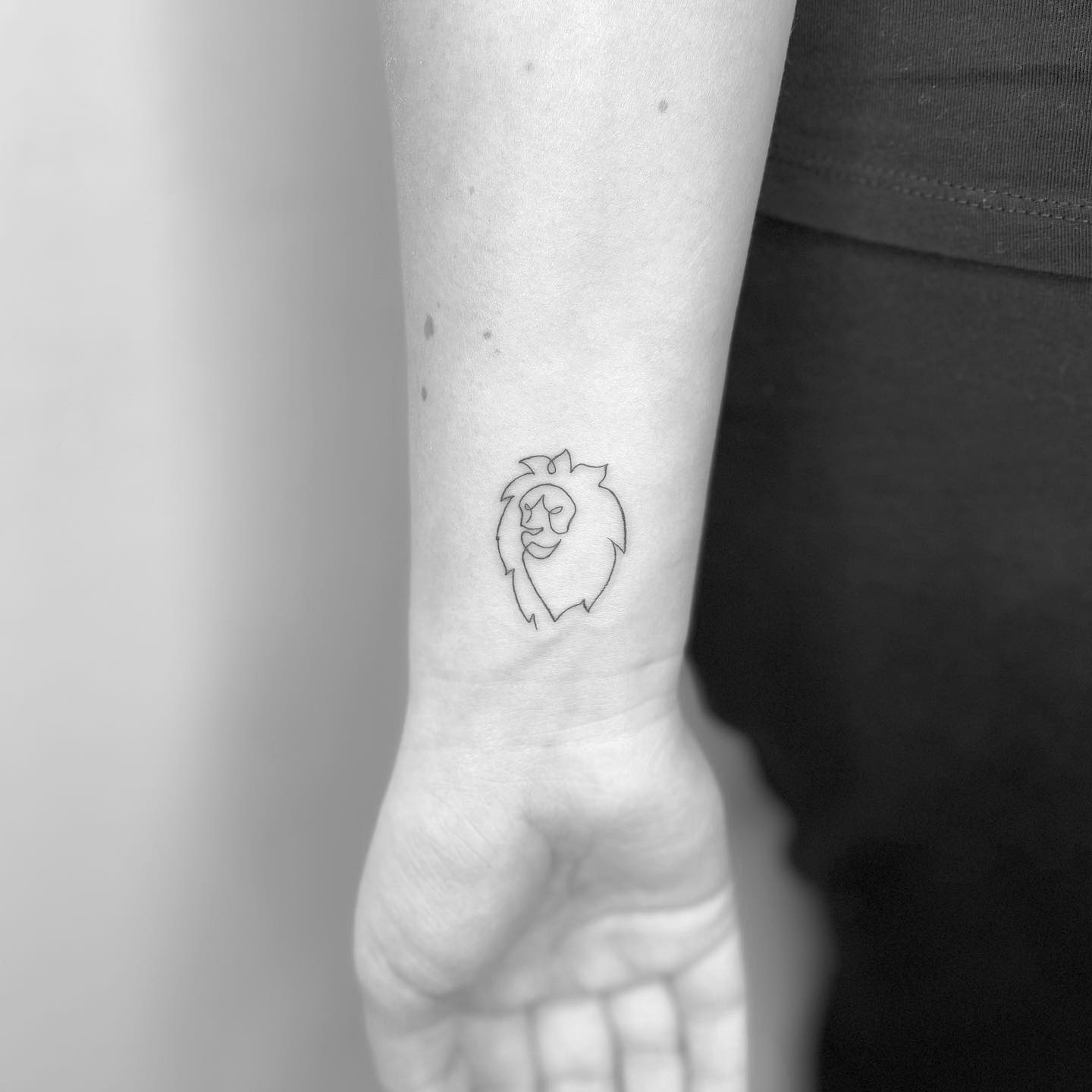 Minimalist single lion tattoo on the wrist