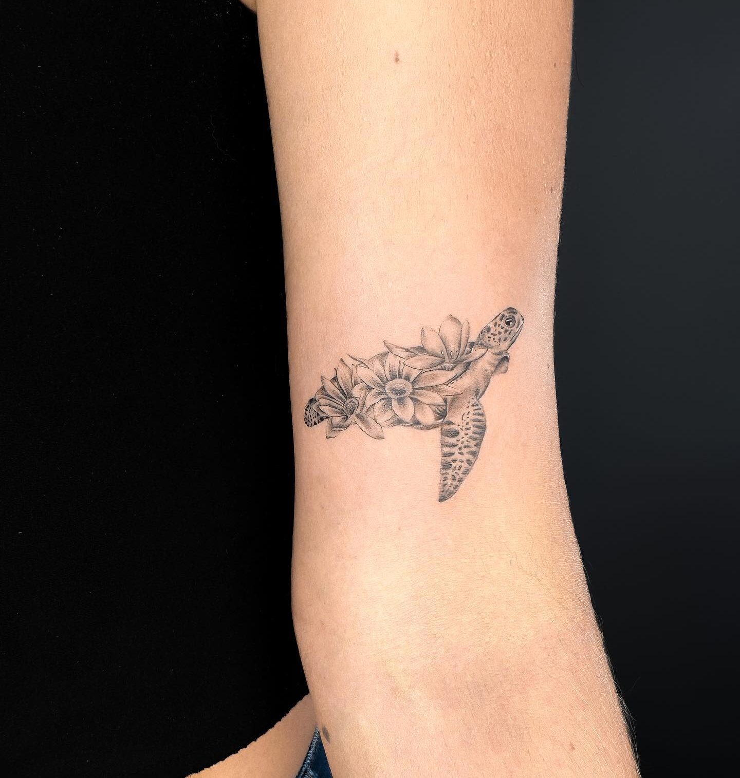 Micro-realistic sea turtle and flowers tattoo on the inner arm