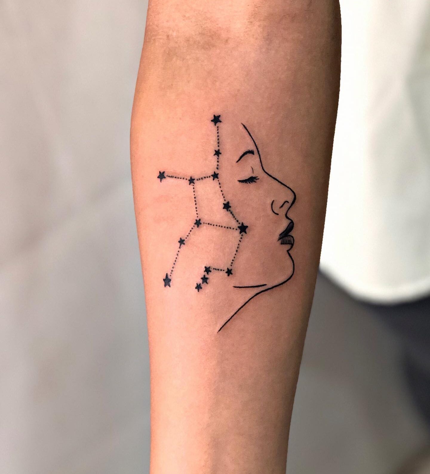 Virgo constellation and face tattoo on the inner forearm