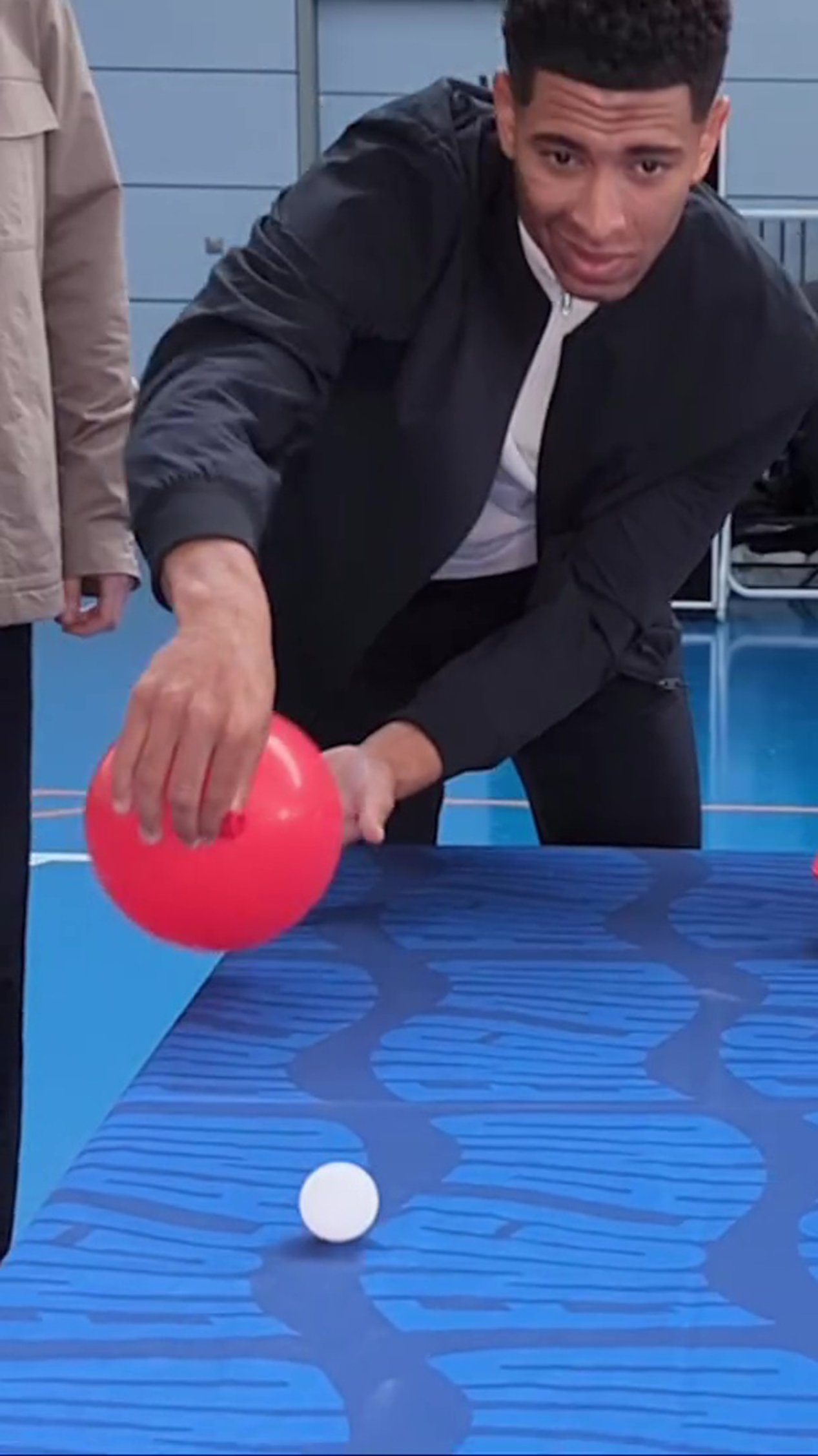 The Three Lions took turns trying to get a ping pong ball in a cup taped to the edge of a table using air from a deflating balloon